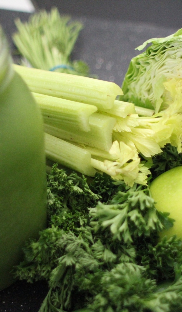 Полезное зеленое смузи на столе с овощами  и зеленью 