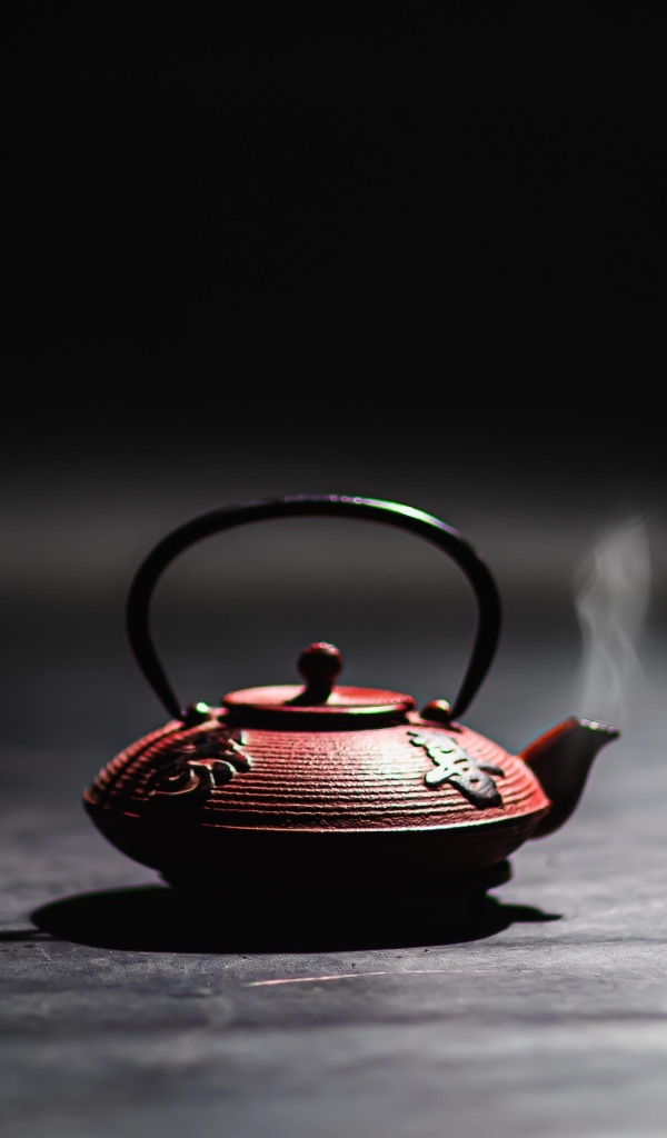 Чайник с горячим чаем на черном фоне