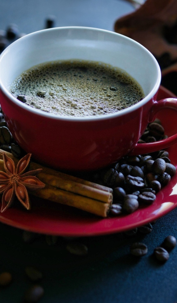 Красная чашка кофе на столе со специями и зернами