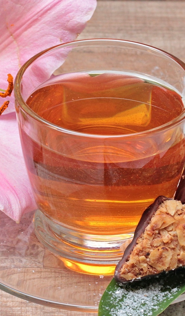 Чай на столе с розовой лилией и конфетами