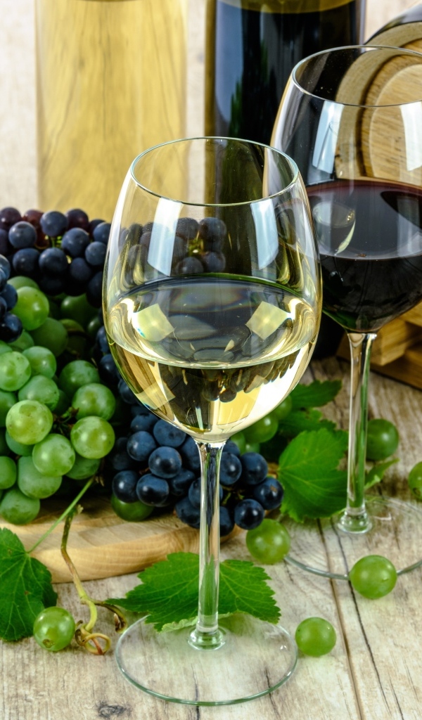 Два бокала вина на столе с виноградом и бочкой