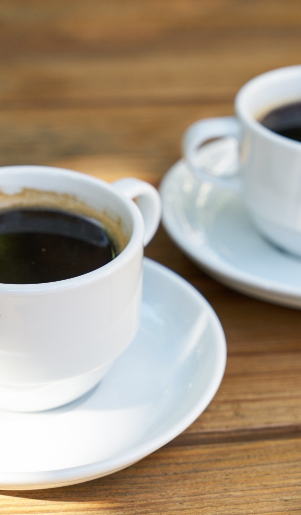 Две белые чашки кофе на столе 