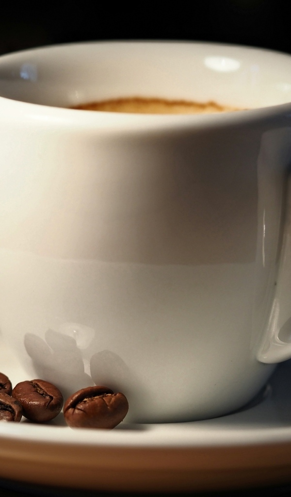 Белая чашка кофе с зернами крупным планом