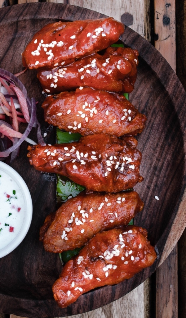 Запеченные куриные крылышки с соусом на тарелке