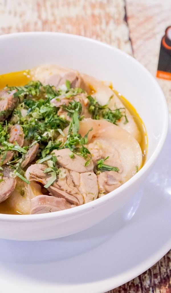 Бульон с мясом в белой тарелке на столе