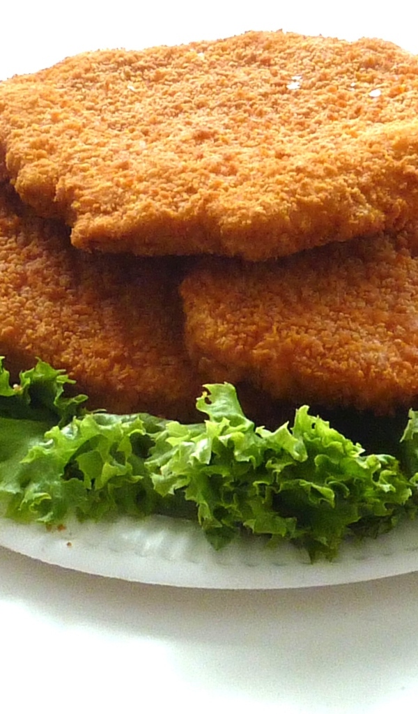 Куриные котлеты с листьями салата на тарелке