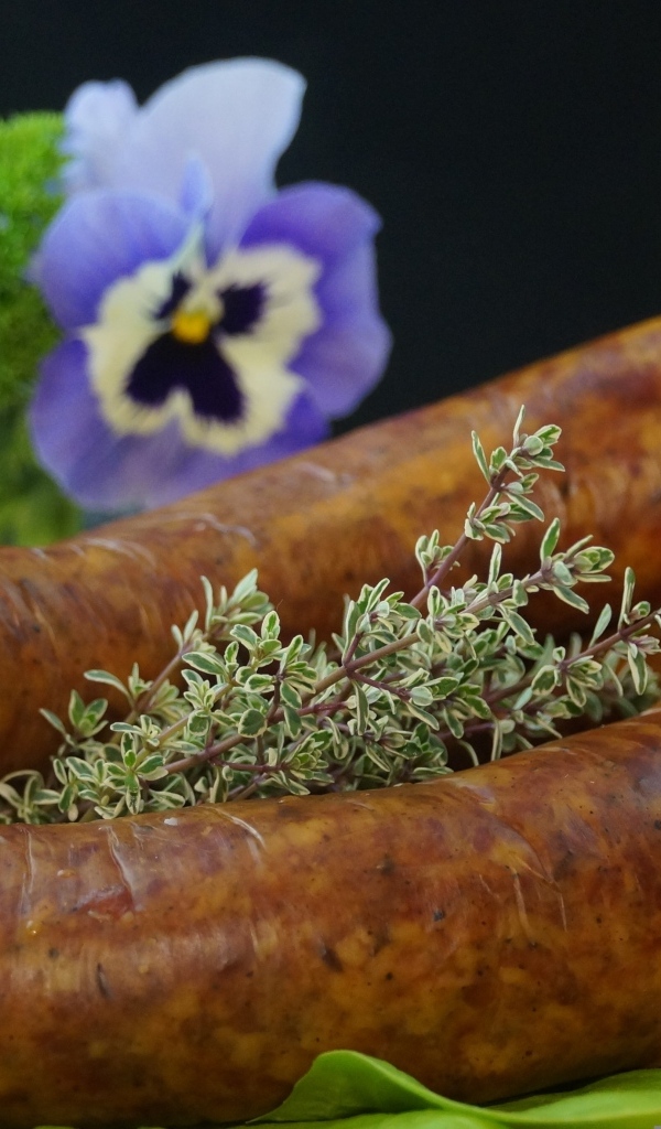 Свежая домашняя колбаса на столе с цветами