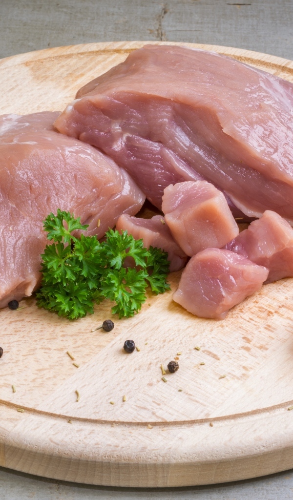 Свежая свинина на разделочной доске с петрушкой