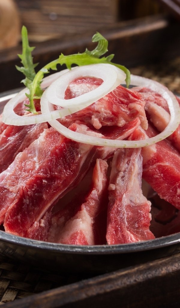 Свежие свиные ребра с луком в миске