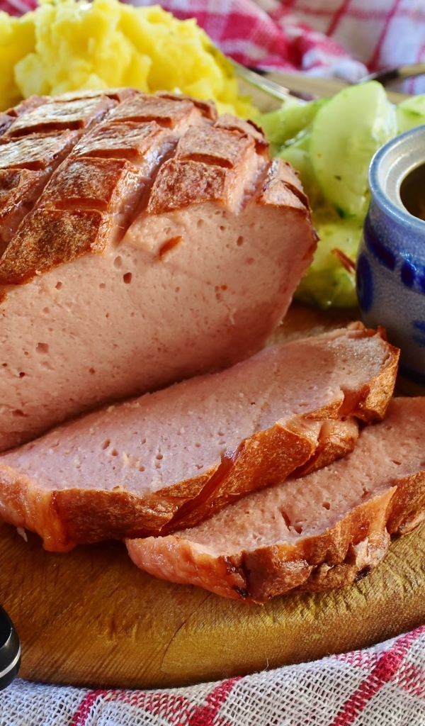 Мясной хлеб на столе с ножом и овощами