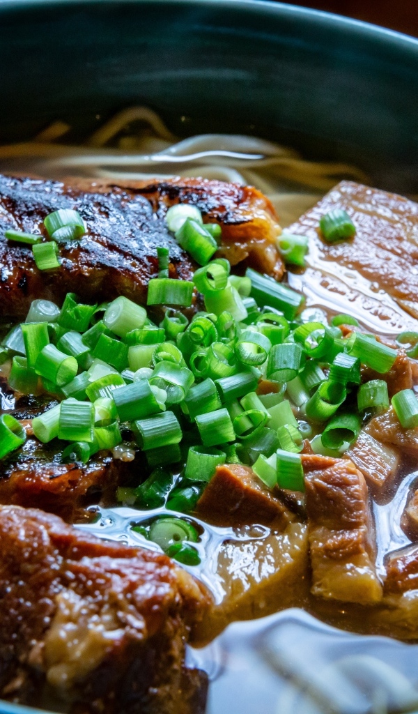 Лапша с мясом и зеленым луком в тарелке