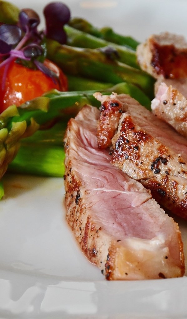 Куски аппетитного мяса на тарелке со спаржей