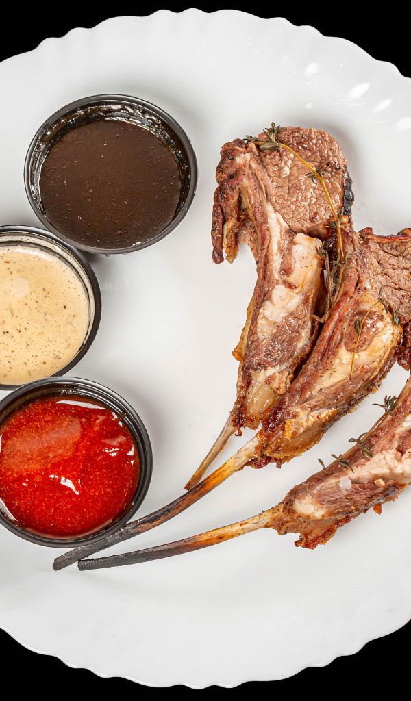 Свиные ребра с соусом на белой тарелке 