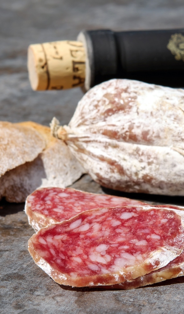 Колбаса салями с хлебом и вином на столе 