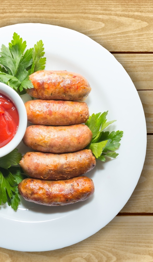 Сардельки на тарелке с соусом и петрушкой