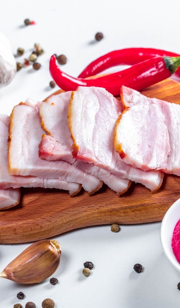 Нарезанное сало на столе с чесноком, хреном и красным перцем