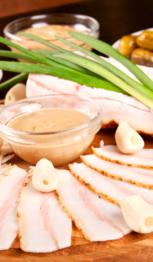 Нарезанное сало с чесноком и солеными огурцами на столе