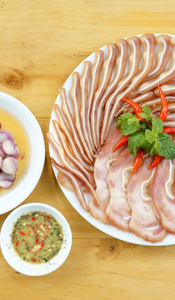 Копченые свиные уши на столе с луком и соусом