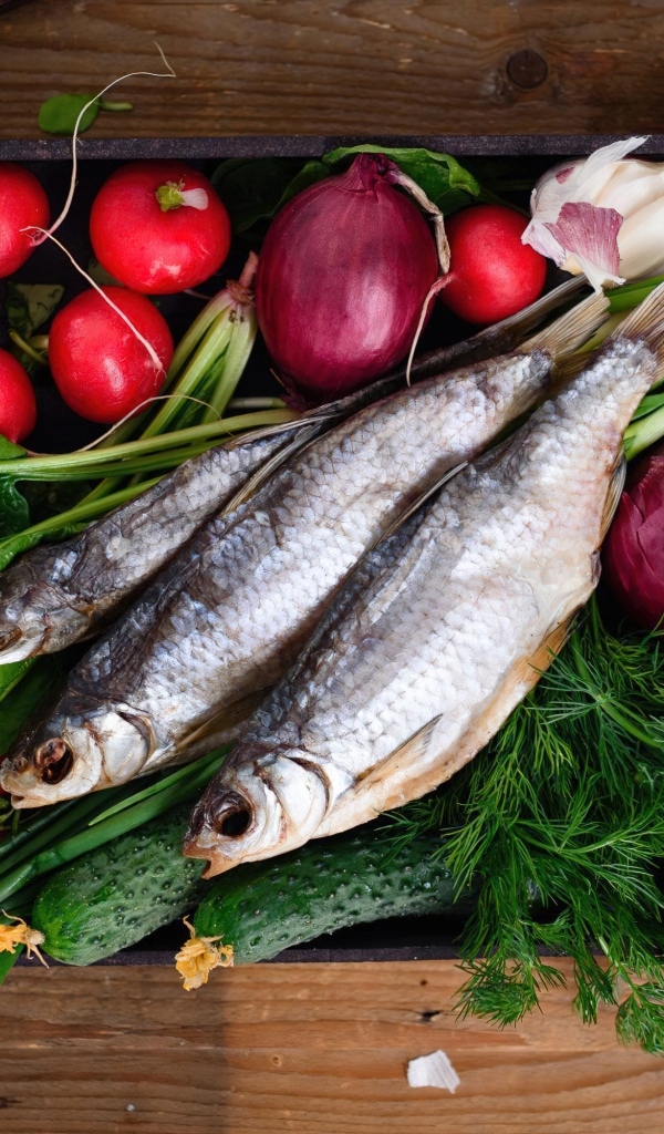 Сушеная рыба на столе с овощами и зеленью 