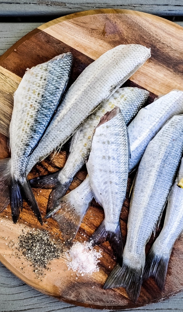 Свежая рыба на доске  с кусочками лимона