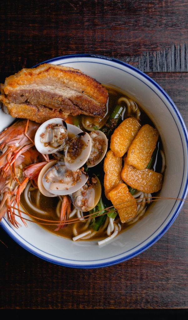 Суп с лапшой и морепродуктами на деревянном столе