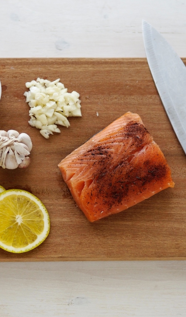 Кусок красной рыбы на доске с лимоном и чесноком
