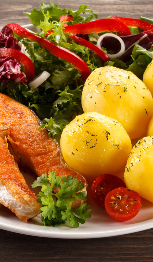 Картофель с кусочками рыбы и зеленью на тарелке