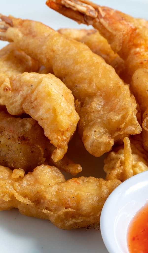 Креветки в кляре на тарелке с салатом и соусом