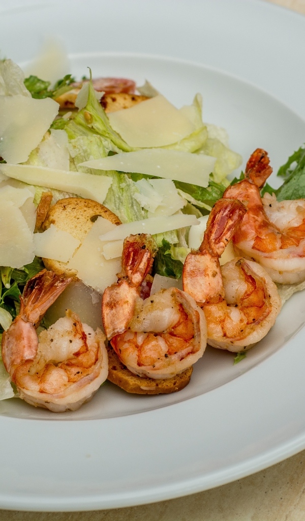 Креветки на тарелке с листьями салата