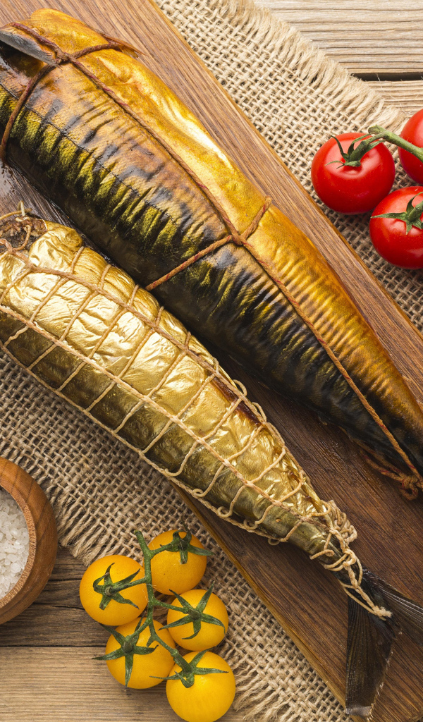 Две копченые скумбрии на столе с помидорами