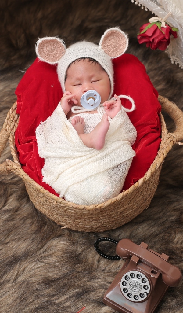 Ребенок спит в корзине с соской во рту