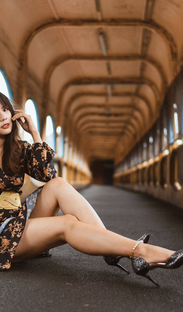 Девушка в красивом коротком платье сидит на полу