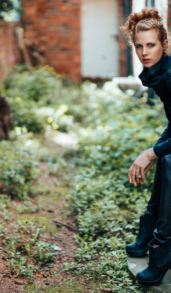 Девушка в черном наряде сидит на окне