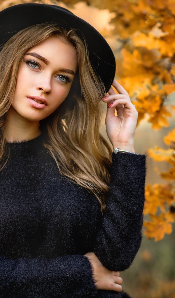 Девушка в черной шляпе стоит у дуба