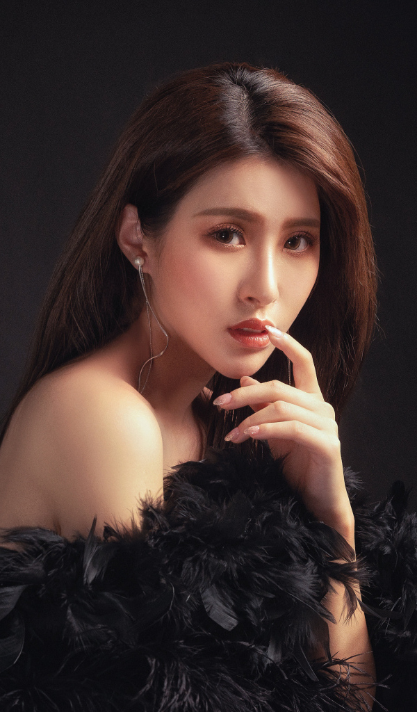 Девушка азиатка в боа на черном фоне