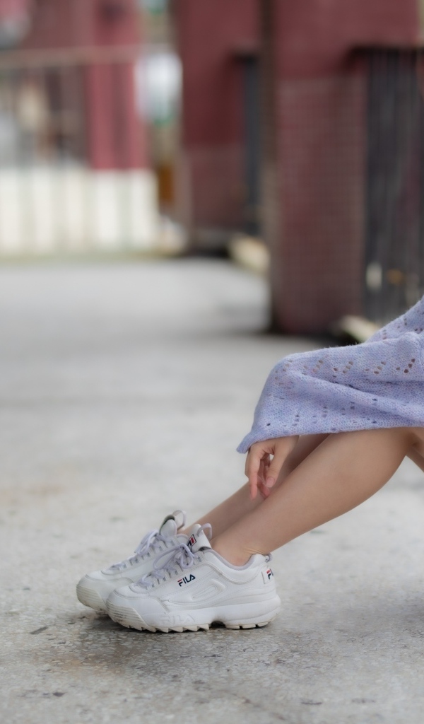 Девушка азиатка в свитере и белых кроссовках 