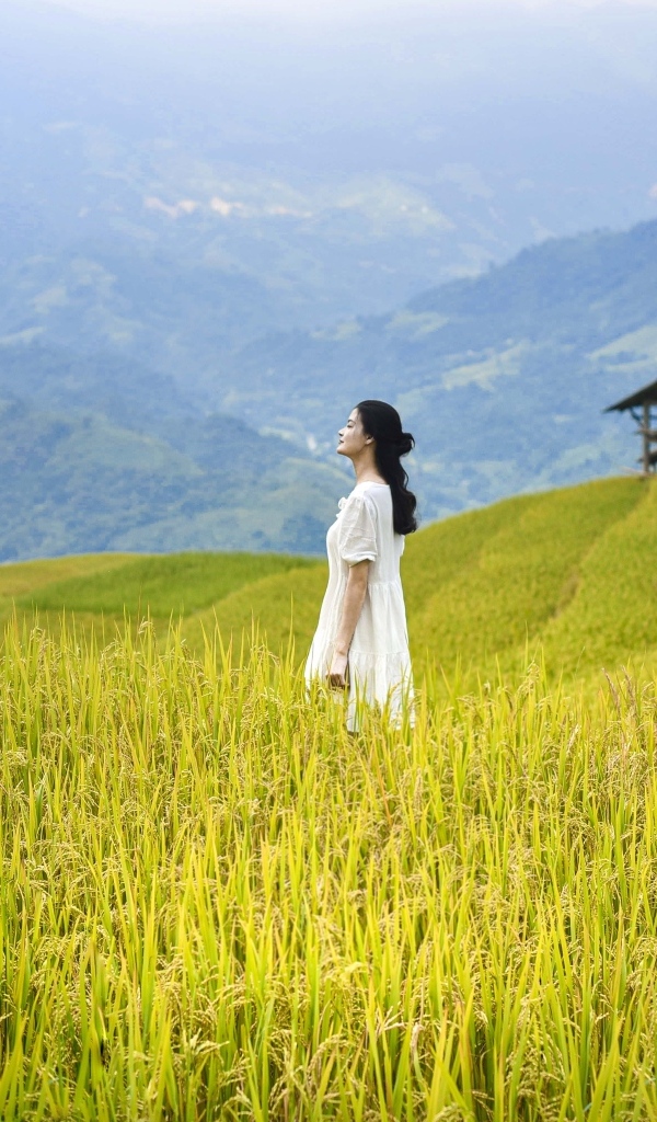 Девушка азиатка в белом платье дышит горным воздухом