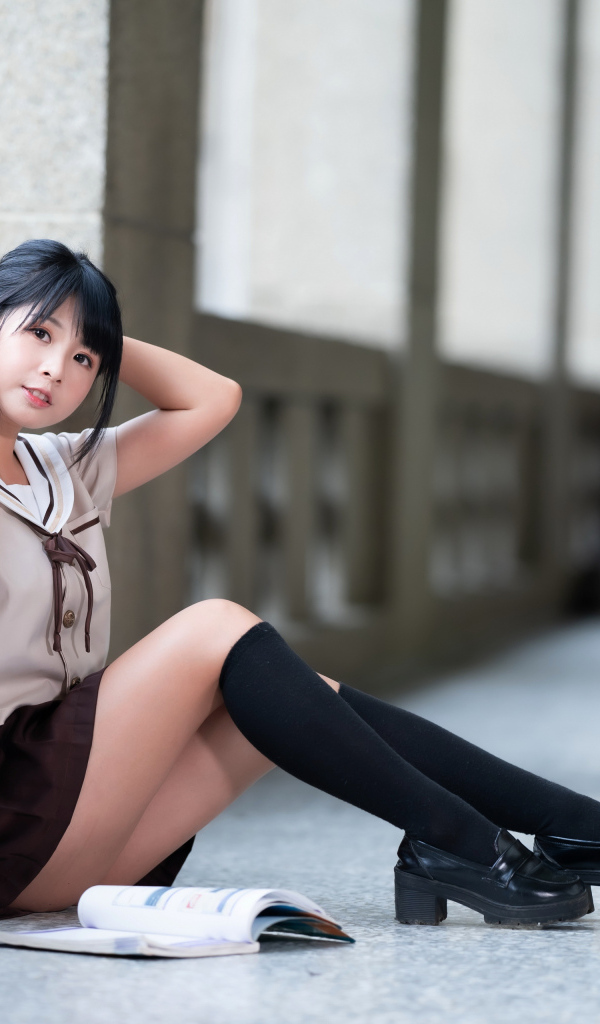 Девушка азиатка в школьной форме сидит на полу