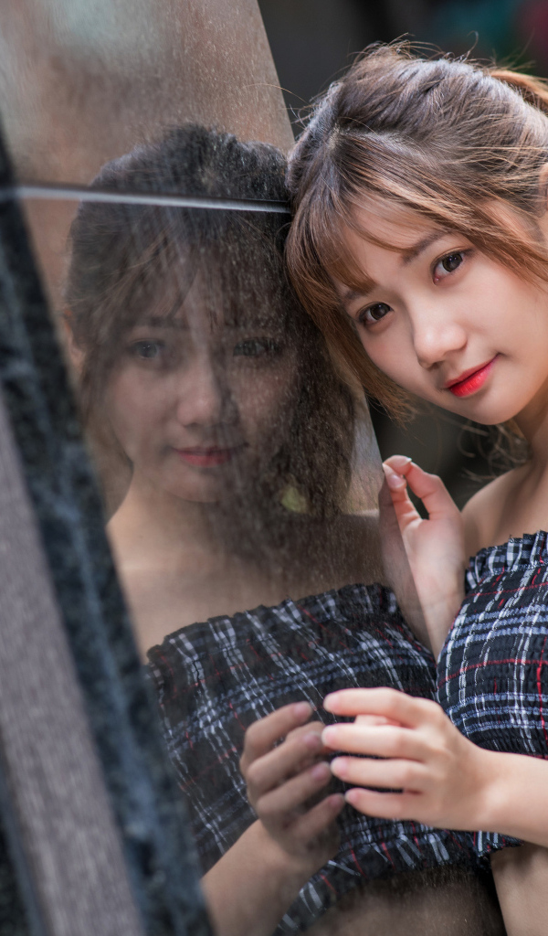 Девушка азиатка отражается в стене