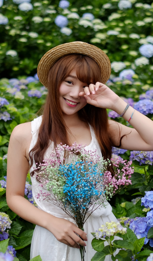 Девушка азиатка у куста с цветами гортензии