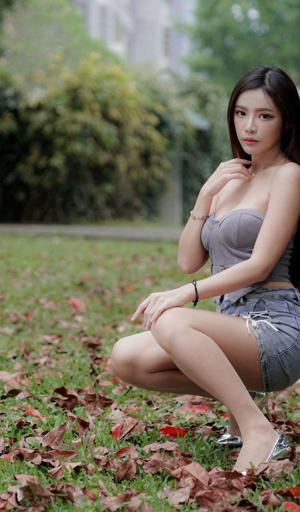 Девушка азиатка на траве в осеннем парке