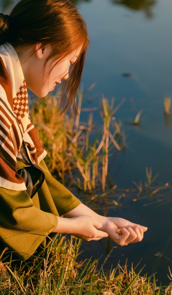 Девушка азиатка сидит у пруда