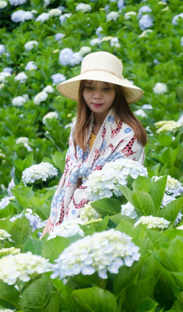 Девушка азиатка сидит в цветах гортензии