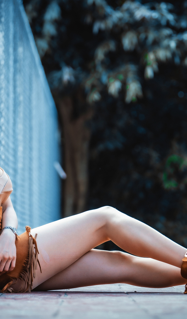 Девушка азиатка сидит на земле у сетки