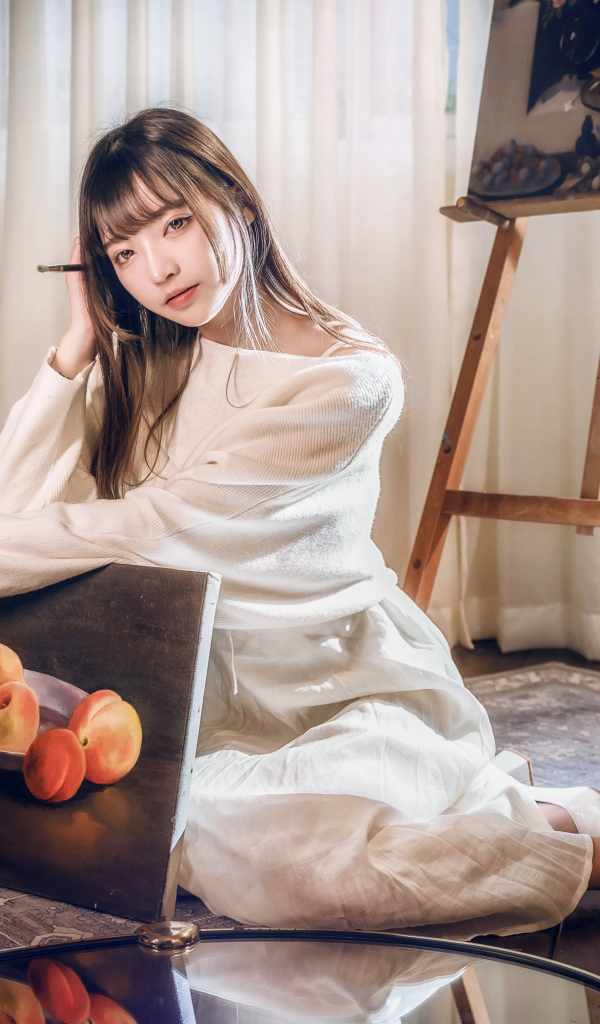 Девушка азиатка сидит с картиной на полу