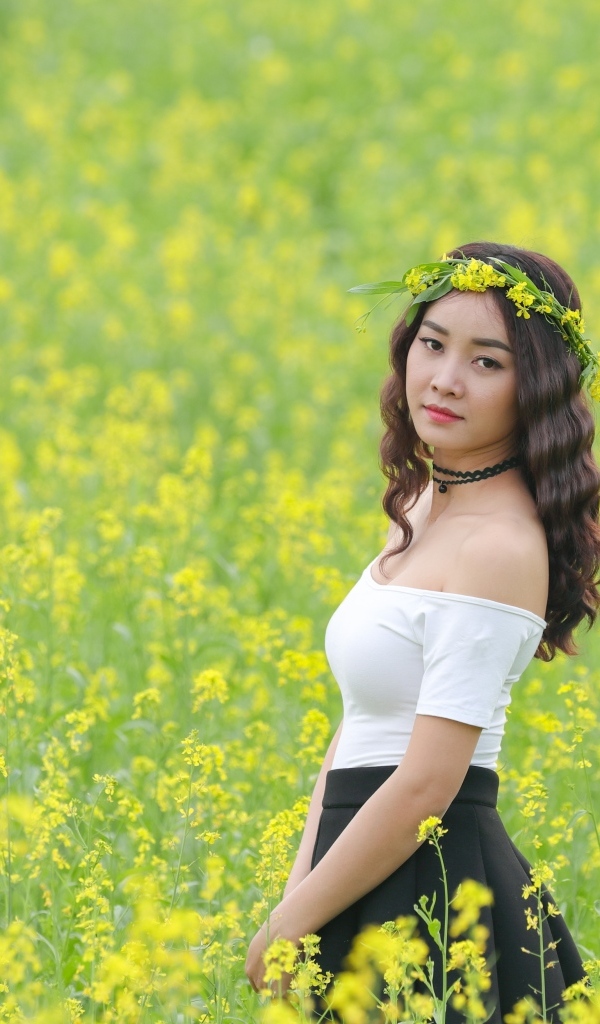 Девушка азиатка стоит на рапсовом поле