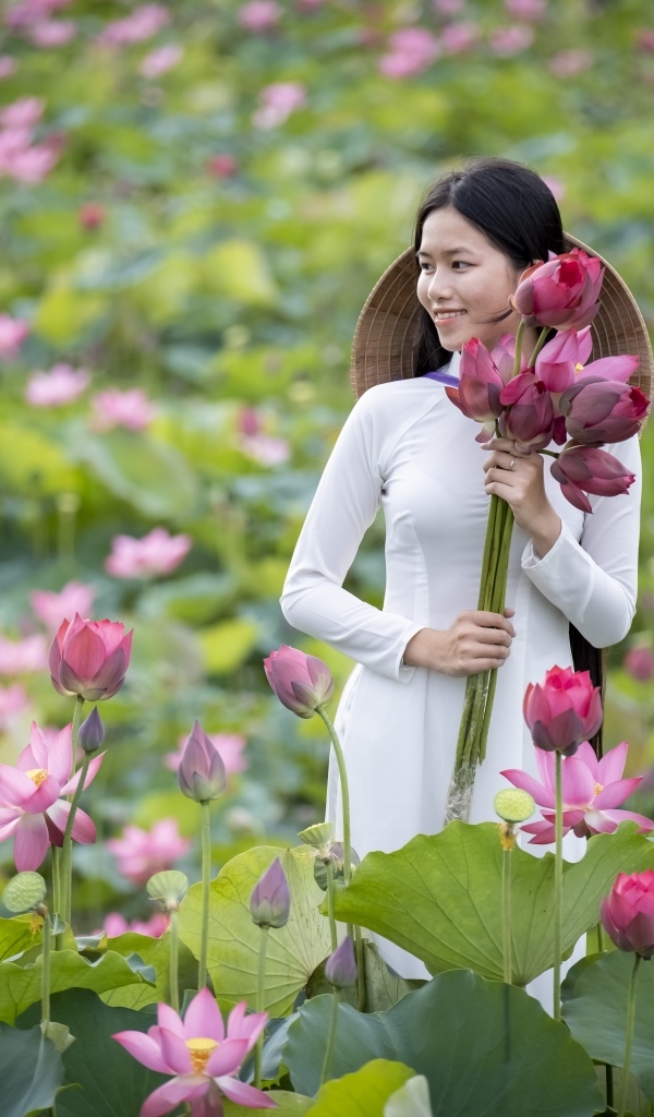 Девушка азиатка с розовыми цветами лотоса в руках