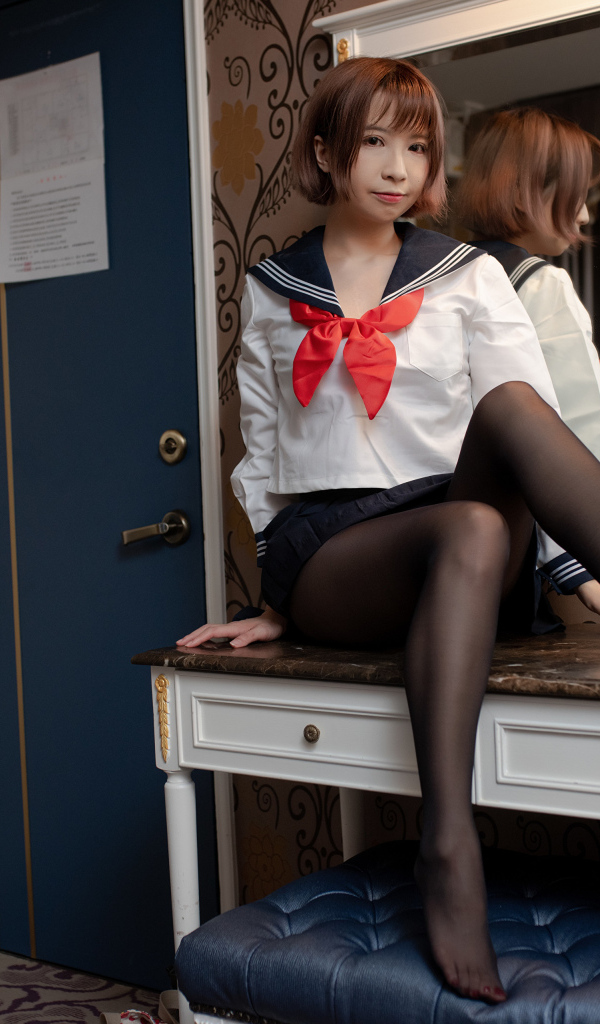 Азиатка в форме сидит на столе