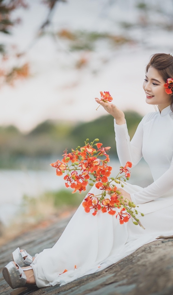 Красивая девушка азиатка в белом платье с цветами в руке