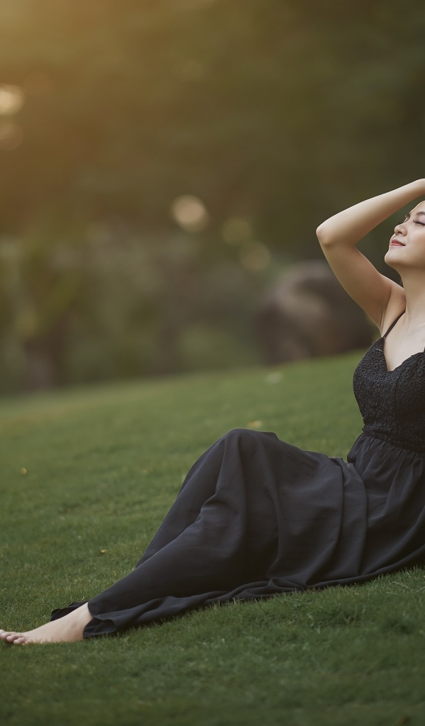 Красивая азиатка с закрытыми глазами в черном платье